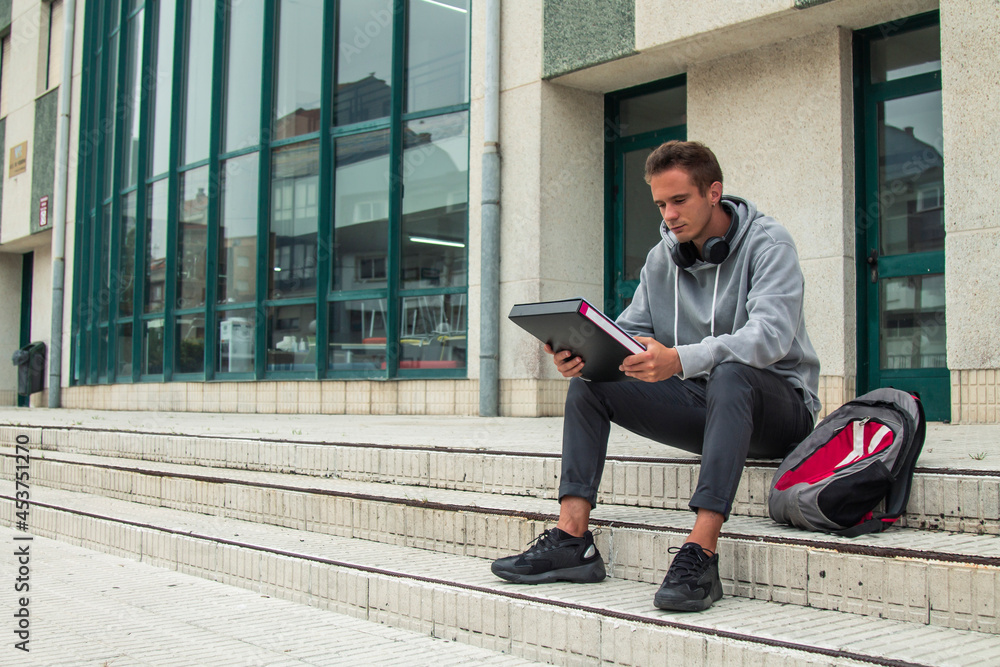young student with headphones sitting in front of institute or university young student with headphones sitting in front of institute or university