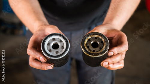 An auto mechanic holds a new and used oil filter. photo