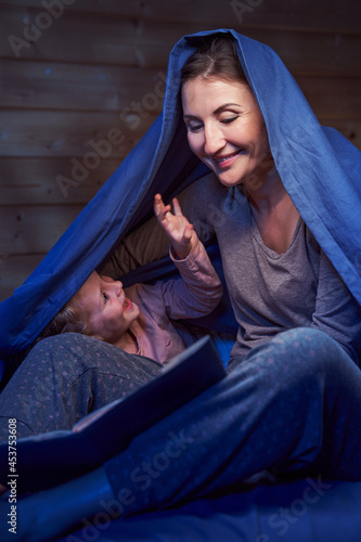 Parent and girl laughing while reading fairy tales