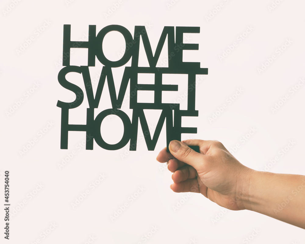 Hand holds wooden phrase Home sweet home. Concept of buying or building home of dreams Hand holds wooden phrase Home sweet home. Concept of buying or building home of dreams