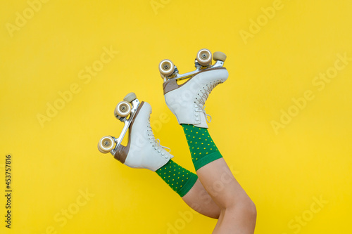 Foto Young woman legs with vintage quad roller skates on yellow background