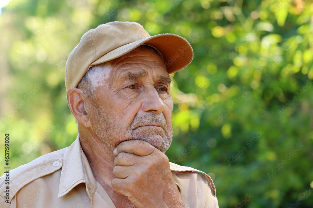 Portrait of pensive elderly man on green nature background. Concept of life in village, old age Portrait of pensive elderly man on green nature background. Concept of life in village, old age