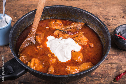 Cooking chicken paprikash, Hungarian stew in a skillet - adding sour cream to chicken stew with paprika.