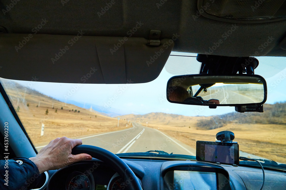 Siberia Baikal, Russia - November 20, 2020: View from of car interior from side of driver to the road and autumn yellow nature landscape with hills through the windshield Siberia Baikal, Russia - November 20, 2020: View from of car interior from side of driver to the road and autumn yellow nature landscape with hills through the windshield