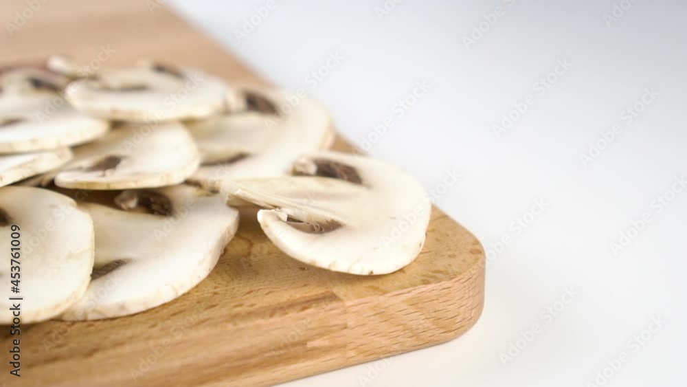 Sliced edible champignon mushroom on a wooden cutting board. Falling slice in slow motion. Close up. Dolly Shot Sliced edible champignon mushroom on a wooden cutting board. Falling slice in slow motion. Close up. Dolly Shot