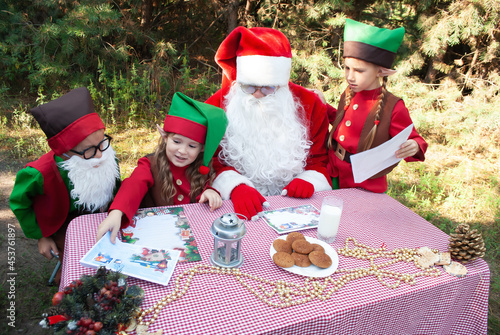 Santa Claus and little elves sort through mail, read letters from children. House, workshop of Santa Claus. Christmas and New Year