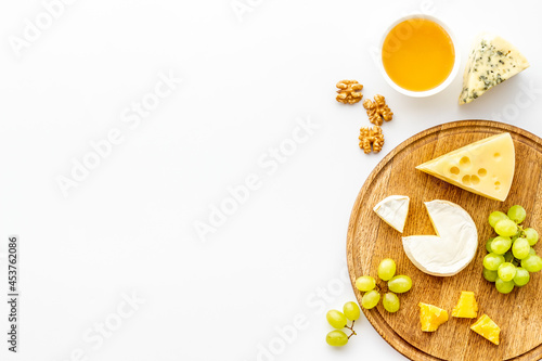 Set of cheese with honey and grapes on wooden board