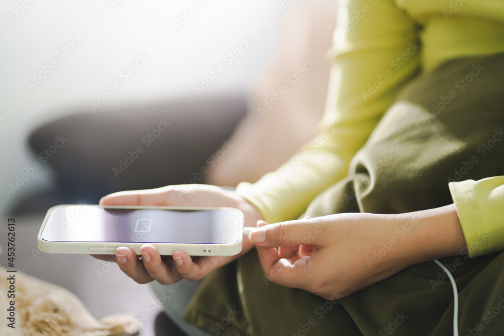 Woman hands Charging mobile phone battery with low battery. plugging a charger in a smart phone  with energy bank powerbank power charger Modern lifestyle energy technology concept.