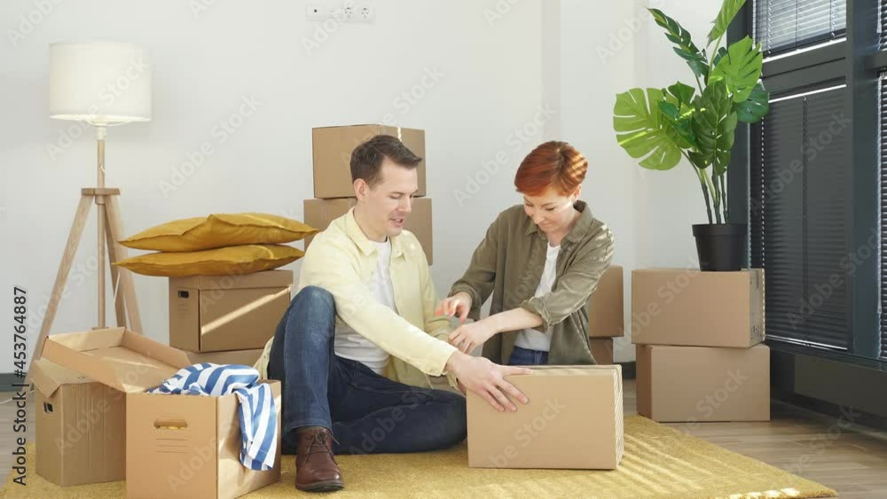 Man And Woman Help Each Other To Pack Stuffs And use Scotch Tape A Box Before Moving To New House. Home Renovation And Relocation Concept Man And Woman Help Each Other To Pack Stuffs And use Scotch Tape A Box Before Moving To New House. Home Renovation And Relocation Concept