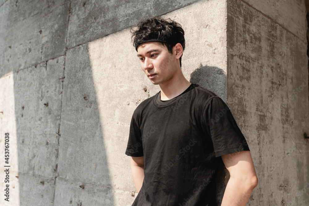 Fototapeta premium Young Asian sportsman leaning against the wall is taking a break