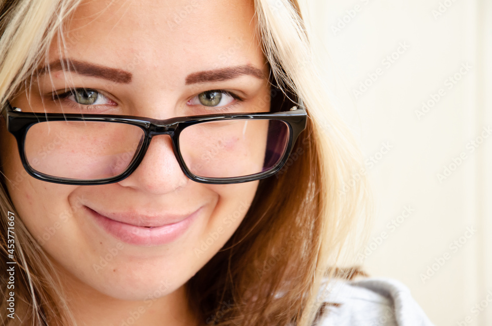 Brunette teen girl with glasses. Health and vision care concept. Happy young woman. Beautiful caucasian young girl with green eyes looks at camera and smales. Acne on young skin.