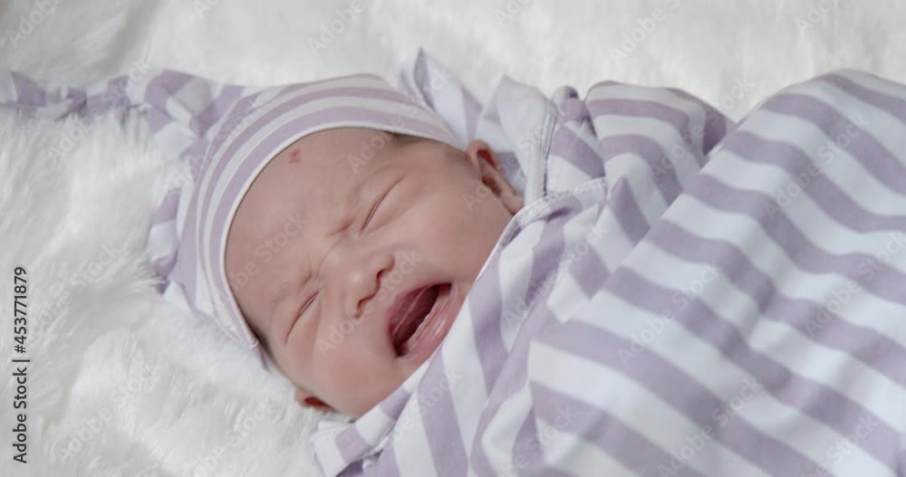 Cute Asian newborn baby girl with angle kiss on forehead waking up and crying for mommy close-up shot. Concept of new life, healthy child, motherhood, maternity, and infant goods. Cute Asian newborn baby girl with angle kiss on forehead waking up and crying for mommy close-up shot. Concept of new life, healthy child, motherhood, maternity, and infant goods.
