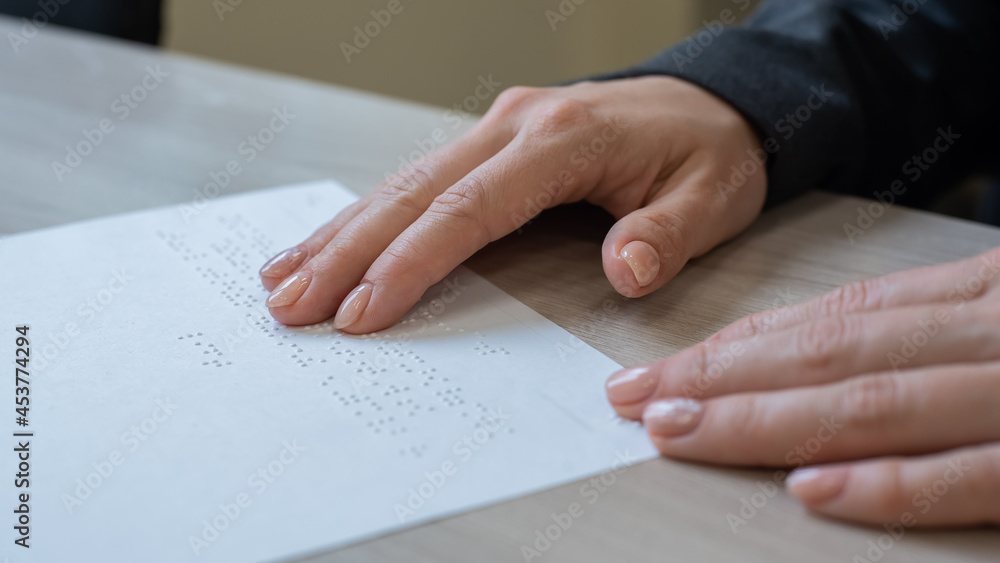 Close-up woman reads the text to the blind. Woman's hands on paper with braille code. Close-up woman reads the text to the blind. Woman's hands on paper with braille code.