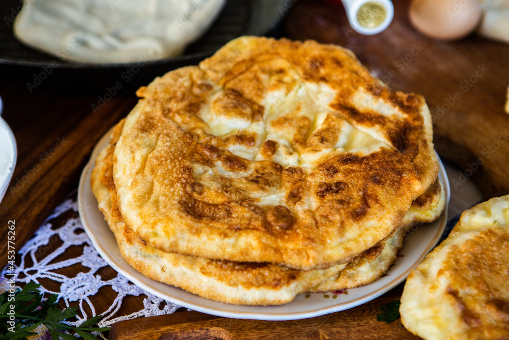 image with the hands of a lady cooking traditional Romanian fried pies with cheese in traditional clothes. image with the hands of a lady cooking traditional Romanian fried pies with cheese in traditional clothes.