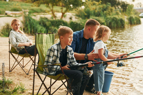 Positive emotions. Father and mother with son and daughter on fishing together outdoors at summertime