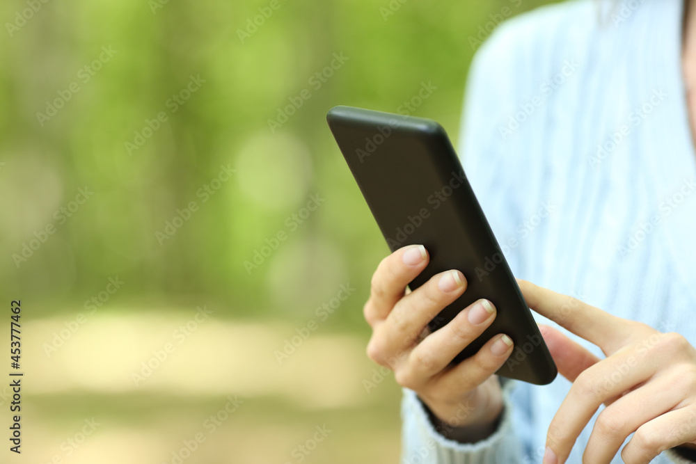 Close up of a woman hands using smart phone in a forest