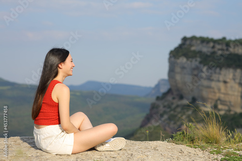 Asian woman contemplating views in a mountain cliff