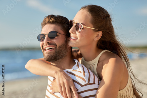 leisure  relationships and people concept - happy couple in sunglasses hugging on summer beach