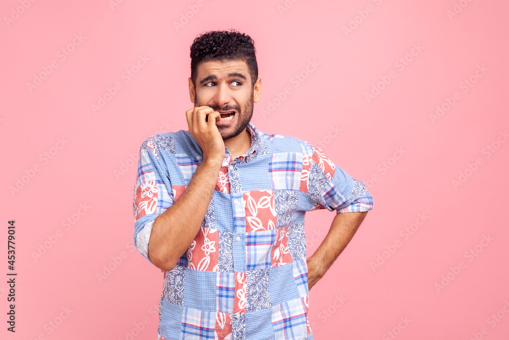 Anxiety disorder. Portrait of stressed out, worried man in blue casual shirt biting nails, nervous about troubles, panicking and looking scared. Indoor studio shot isolated on pink background. Anxiety disorder. Portrait of stressed out, worried man in blue casual shirt biting nails, nervous about troubles, panicking and looking scared. Indoor studio shot isolated on pink background.