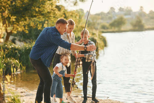 Weekend activities. Father and mother with son and daughter on fishing together outdoors at summertime