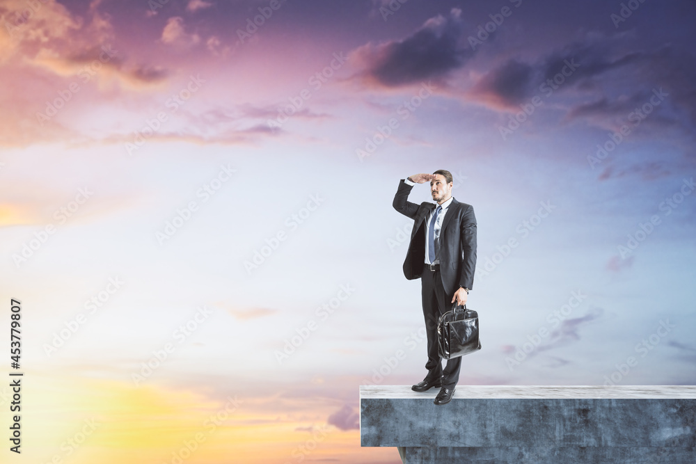 Man on abstract concrete edge looking into the distance on creative bright sky background with mock up place. Future, tomorrow and success concept. Man on abstract concrete edge looking into the distance on creative bright sky background with mock up place. Future, tomorrow and success concept.