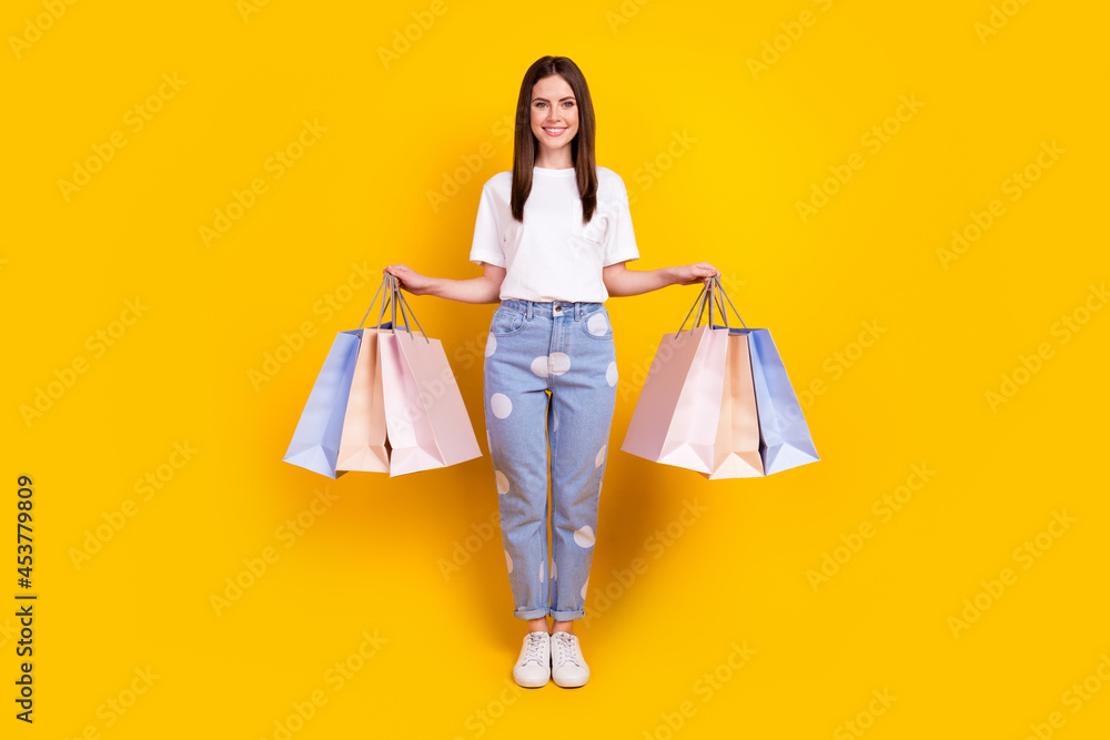Full size photo of happy smiling good mood beautiful woman hold shopping bags isolated on yellow color background