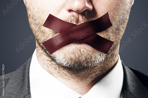 Close up of taped caucasian businessman mouth. Silence and speech censorship concept. photo
