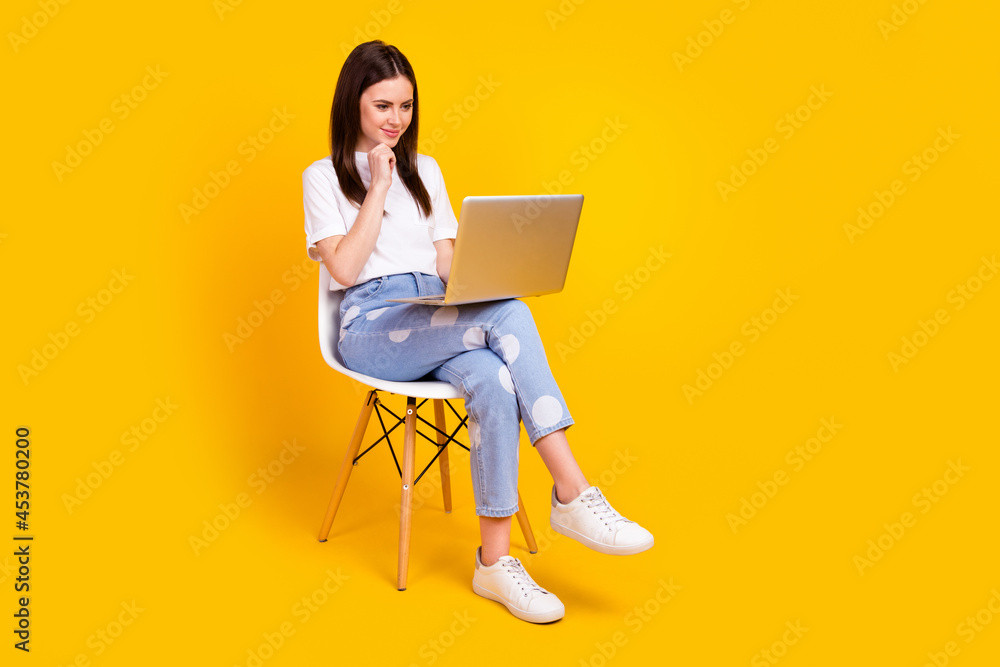 Naklejka premium Full length profile side photo of young woman happy smile sit chair look laptop think report isolated over yellow color background