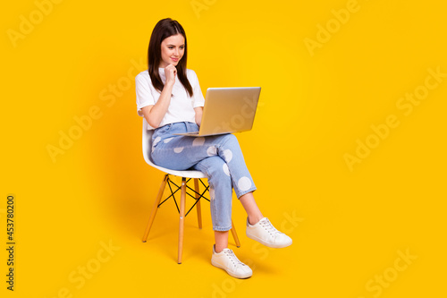 Full length profile side photo of young woman happy smile sit chair look laptop think report isolated over yellow color background