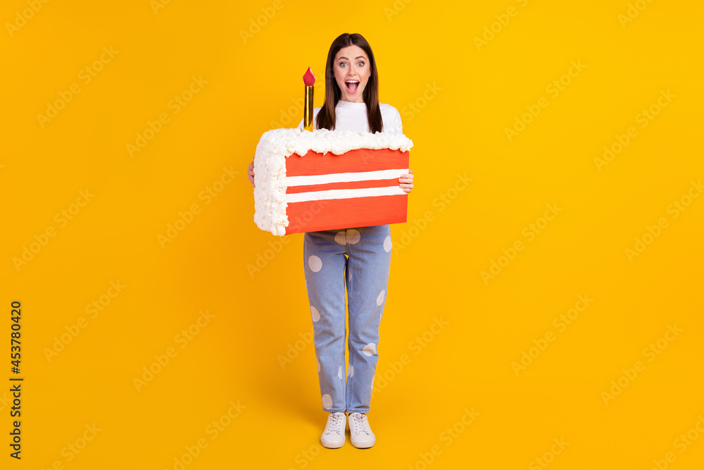 Full length photo of young excited woman amazed surprised hold birthday cake isolated over yellow color background Full length photo of young excited woman amazed surprised hold birthday cake isolated over yellow color background