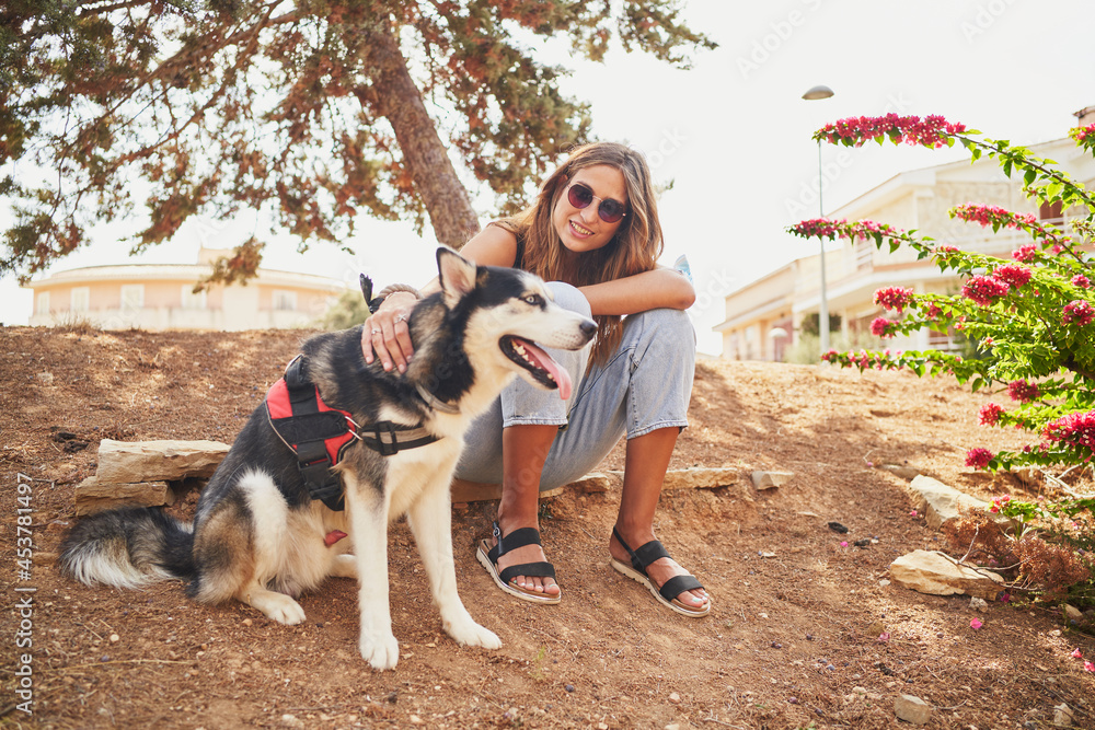 Young spanish woman sitting in park with her siberian husky