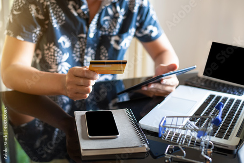 Male use credit card to shopping online in internet website shop with computer laptop on work table in office.