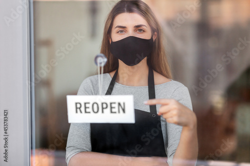 small business, reopening and service concept - woman in black mask with reopen banner on window or door glass © Syda Productions