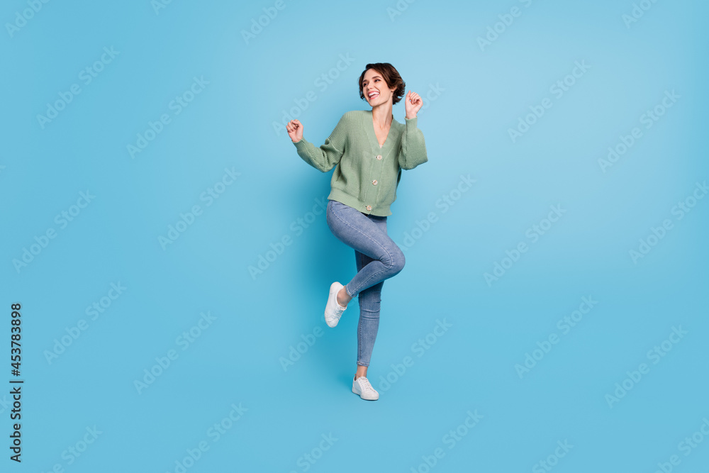 Full length photo of shiny charming young girl dressed green cardigan dancing isolated blue color background
