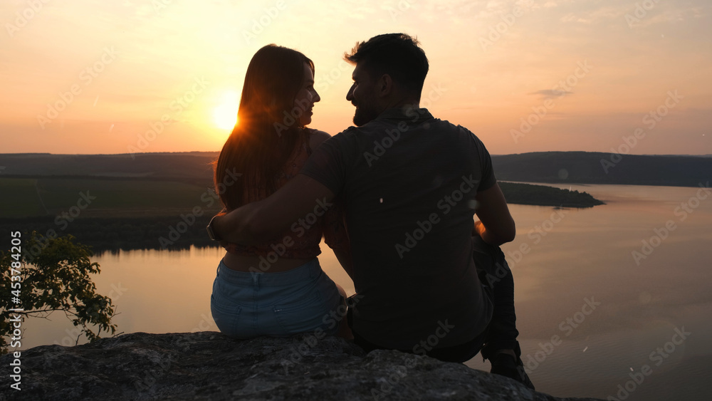 The romantic couple sitting on the rocky mountain top