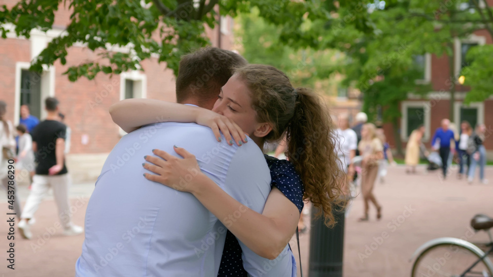 Young man and woman meeting and hugging in summer park