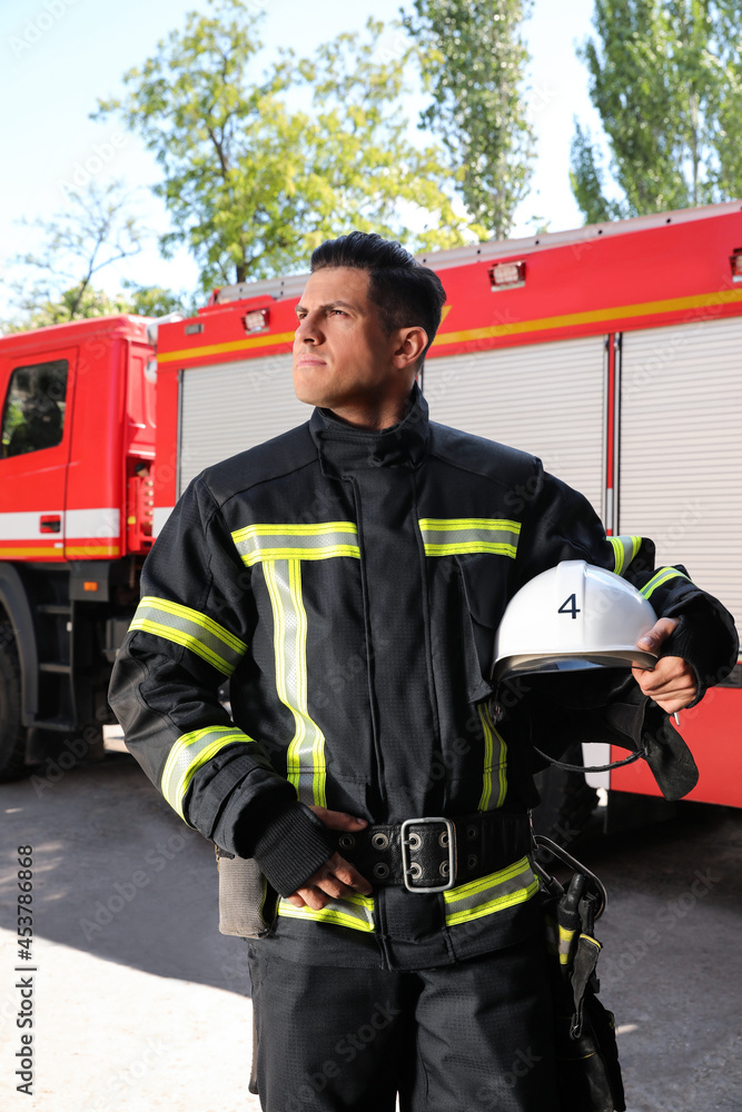 Portrait of firefighter in uniform with helmet near fire truck outdoors Portrait of firefighter in uniform with helmet near fire truck outdoors