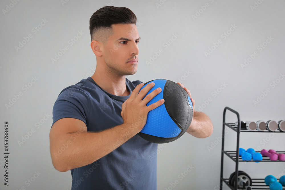 Muscular man exercising with medicine ball in modern gym