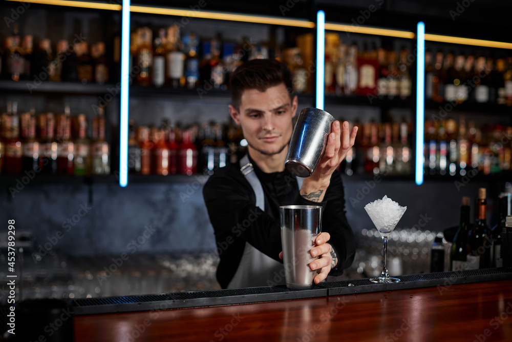 barman shaking tasty cocktail at the bar
