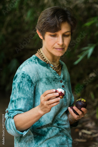 woman eats mangosteen in nature, vegetarian concept