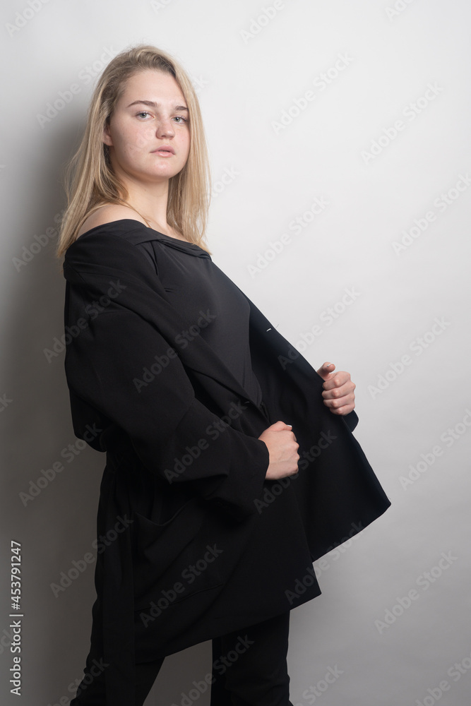 Girl, blonde, shoulder-length hair. Posing in the studio on a light background. Black clothes. Spring summer type. Baby face.