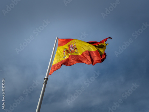 Low angle shot of a waving Spanish flag on the background of the sky photo