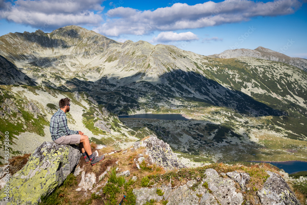 handsome man sitting on mountain top in amazing summer landscape