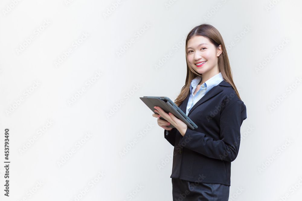 Asian business woman in black suit smiles happily while she works and holds tablet on white background. Asian business woman in black suit smiles happily while she works and holds tablet on white background.