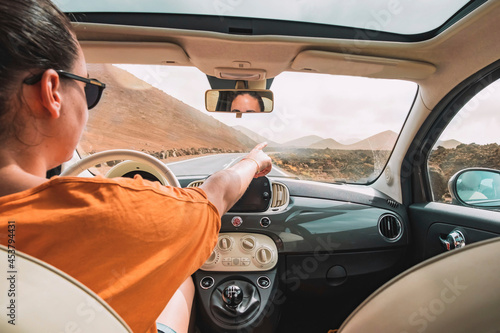 A Caucasian woman points her finger at something while driving a car on a highway. Travel concept.