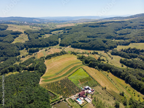 Aerial view of remote house with swimming pool, lake and orchard. Summer 2021