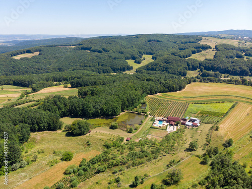 Aerial view of remote house with swimming pool, lake and orchard. Summer 2021
