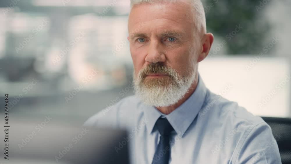 Confident Senior Businessman Using Desktop Computer in Modern Office with Colleagues. Stylish Experienced Manager Working on Commercial, Financial and Marketing Projects. Specialist in Diverse Team. Confident Senior Businessman Using Desktop Computer in Modern Office with Colleagues. Stylish Experienced Manager Working on Commercial, Financial and Marketing Projects. Specialist in Diverse Team.