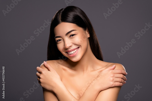 Photo of cheerful korean lady hands hug sensitive shoulders shiny smile look camera isolated grey color background