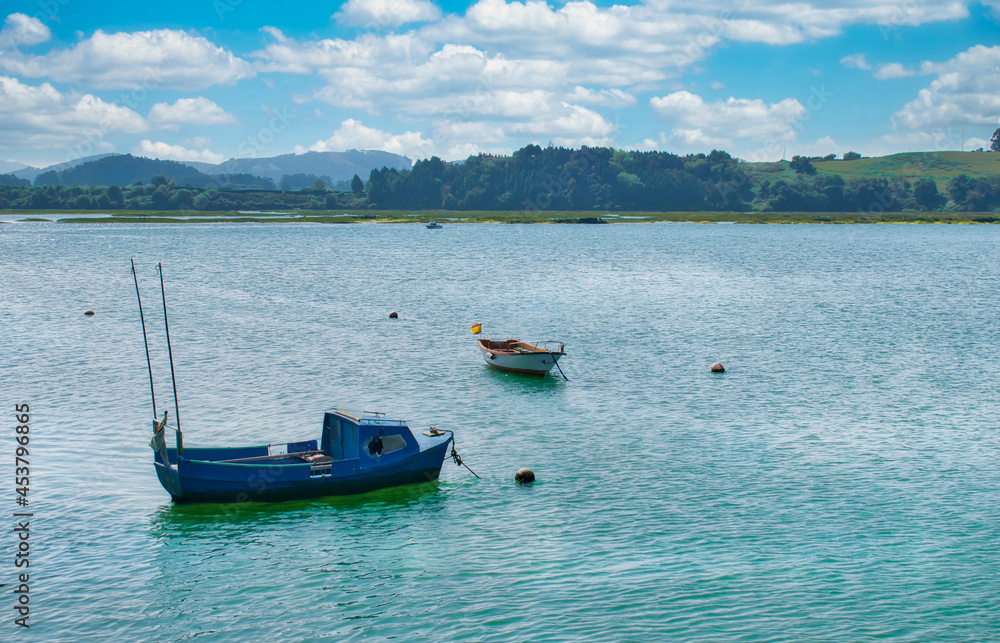 Barcas de madera flotando en las aguas del parque natural de las marismas de Santoña, Victoria y Jayel en Cantabria, España